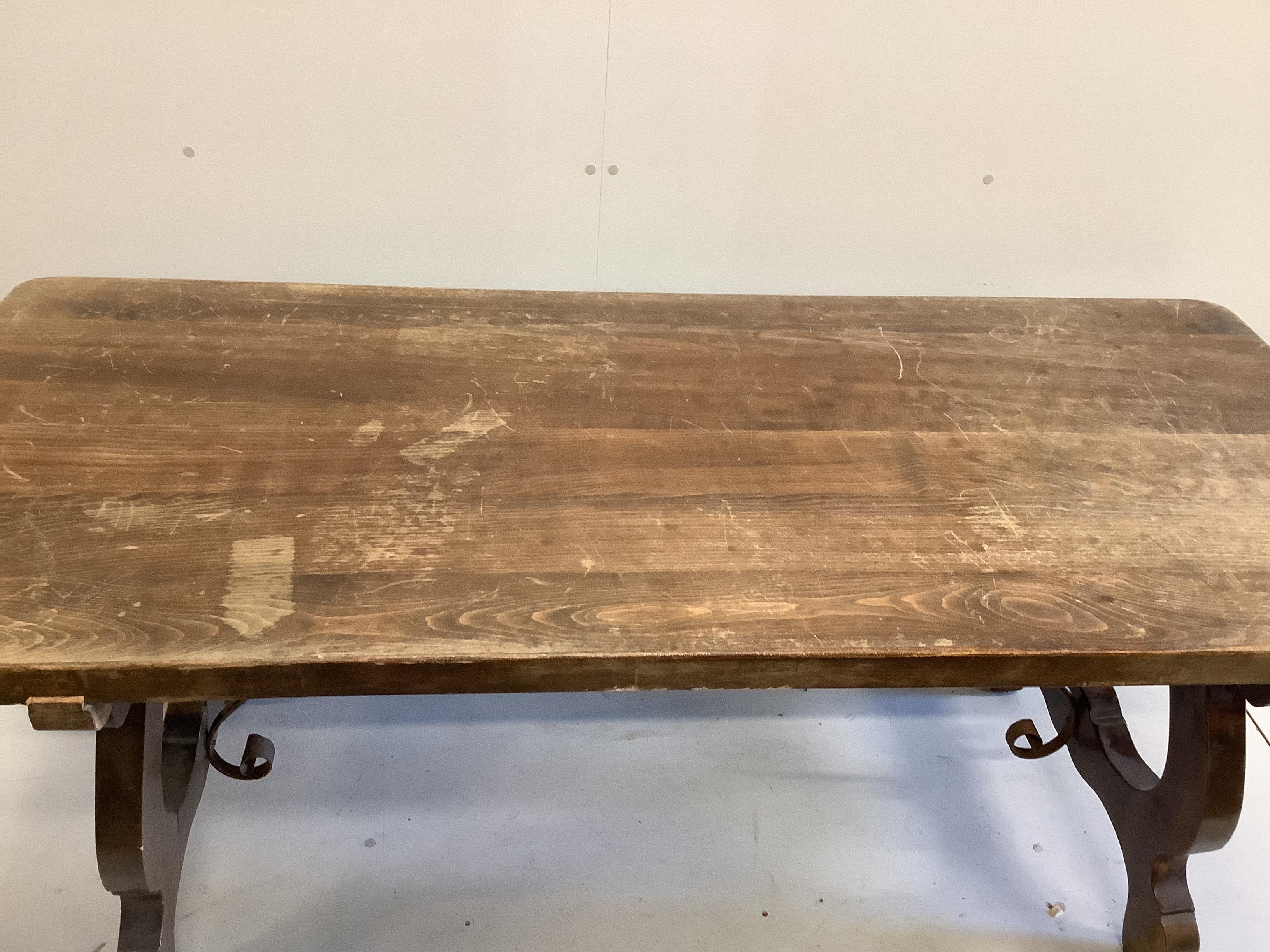 A Spanish style beech rectangular dining table, on shaped supports with iron stretcher, length 180cm, width 78cm, height 74cm